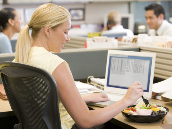 Businesswoman using laptop and eating salad