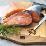 Raw salmon fish steaks with fresh herbs on cutting board