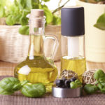 Two bottles with olive oil and grape seed oil with decoration of fresh basil and olives