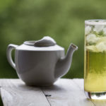 With long green ice tea and glass teapot on unfocused background