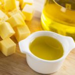 Olive oil in small glass container with bottle of oil and cubes of butter