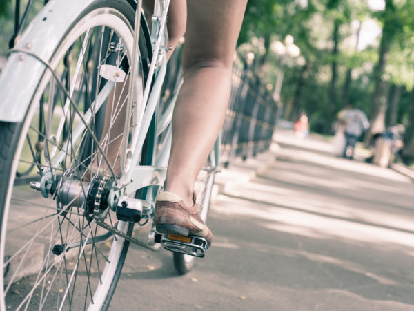 closeup woman riding by blue vintage city bicycle at the city center. It is like concept for activity and healthy lifestyle and environmentally friendly transport