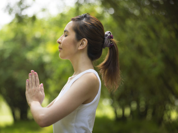 Young Asian woman practicing yoga in a garden. healthy lifestyle and relaxation