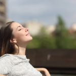 Urban woman sitting on a bench of a park and breathing deep fresh air