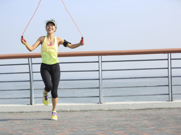 young fitness woman jumping rope at  seaside