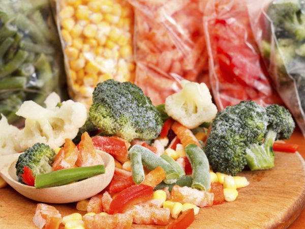 Mixed frozen vegetables on cutting board and plastic bags