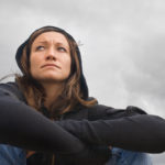 Girl sitting and contemplating on a background of a cloudy sky