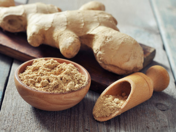 Fresh ginger root and ground ginger spice on wooden background