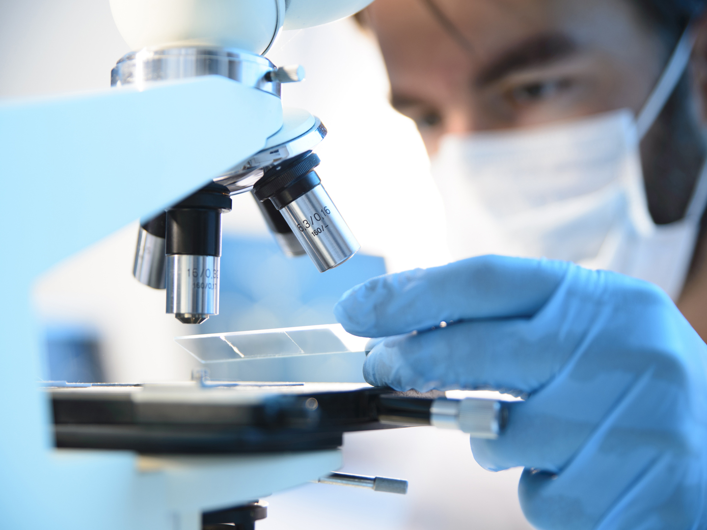 A scientist placing a slide under a microscope