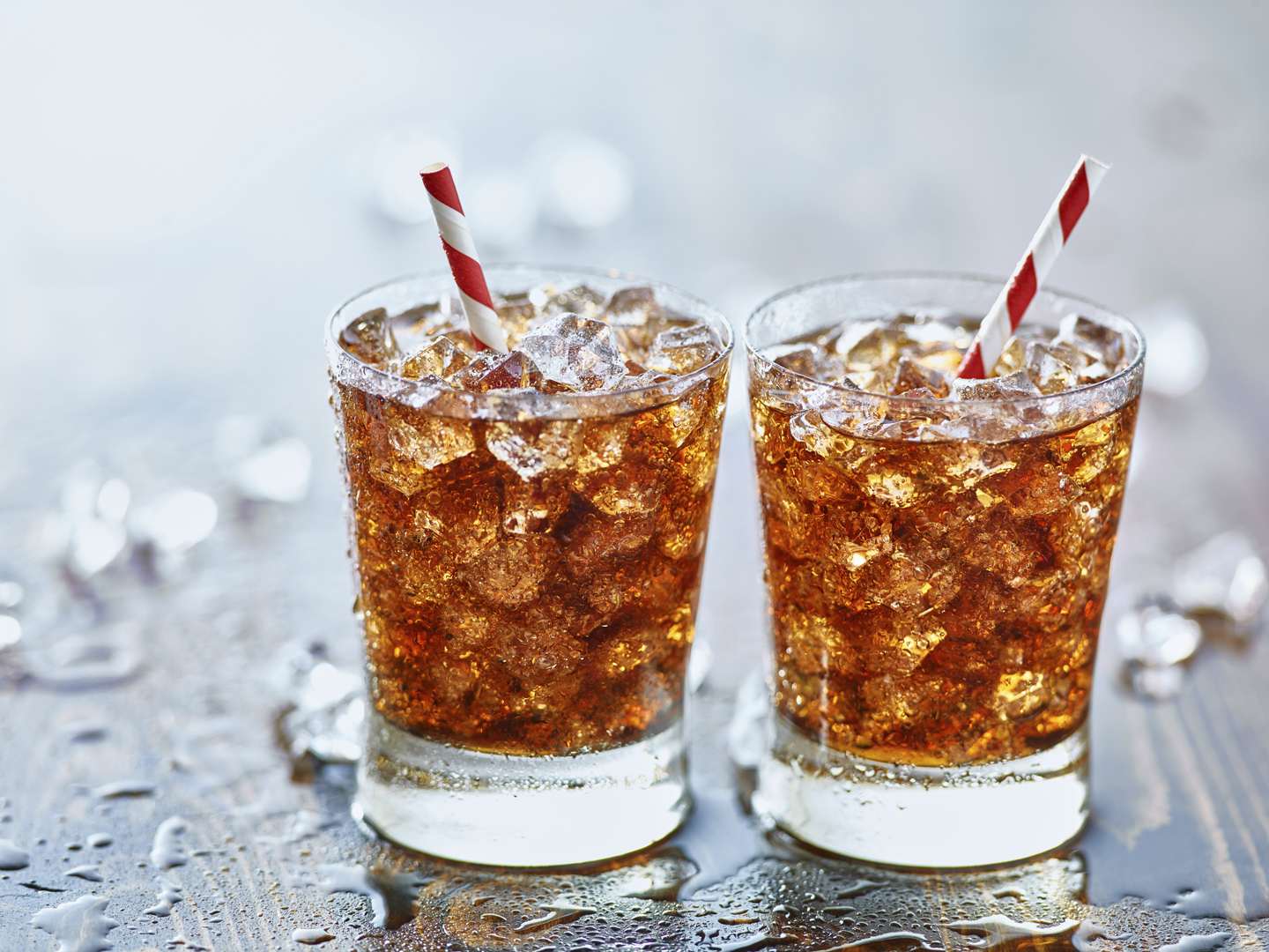 side by side glasses of ice cold cola soda pop with retro striped straws