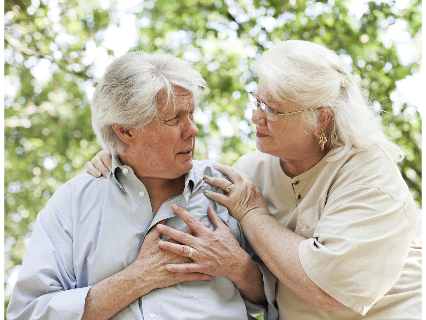 A senior man experiencing chest pain.  A senior woman comforts him.