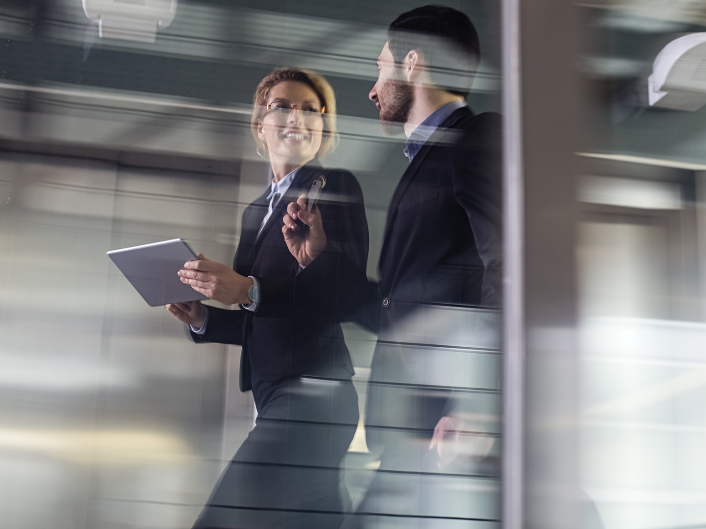 Business professionals having a conversation while passing through office building lobby.