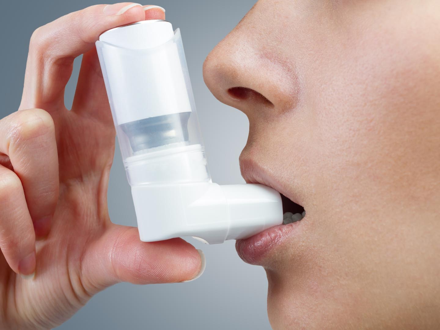 Woman uses an inhaler during an asthma attack, close-up