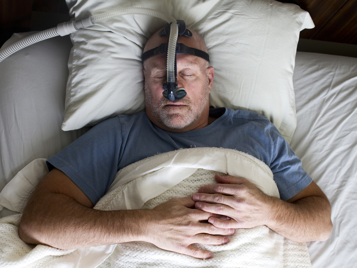 Photo of a man sleeping while wearing a CPAP mask.