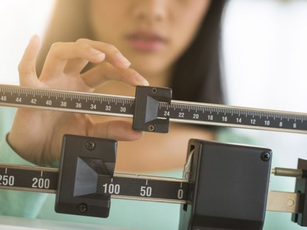 Midsection of mid adult Asian woman adjusting balance weight scale