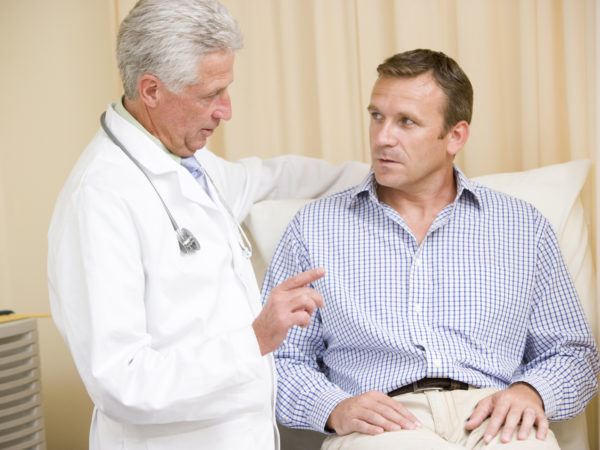 Doctor giving middle-aged man checkup in exam room