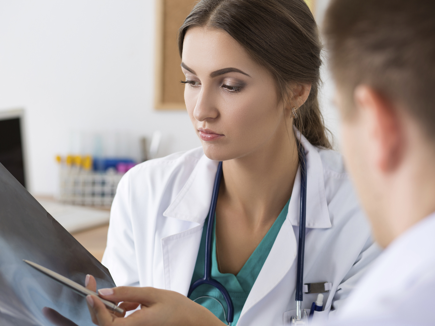 Female medicine doctor showing something to her male colleague on x-ray image. Healthcare and medical concept