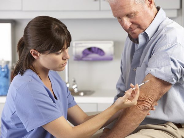 Doctor Giving Male Patient Injection In Hospital Room