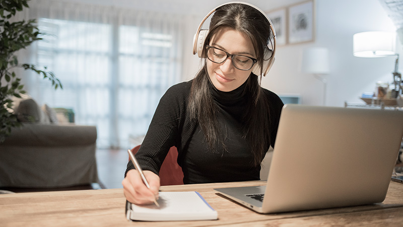 Woman with headphones working on laptop