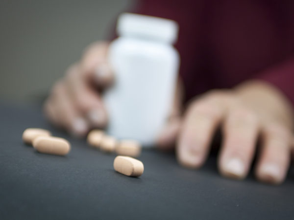 Hands Of Woman Deformed From Rheumatoid Arthritis holding pills