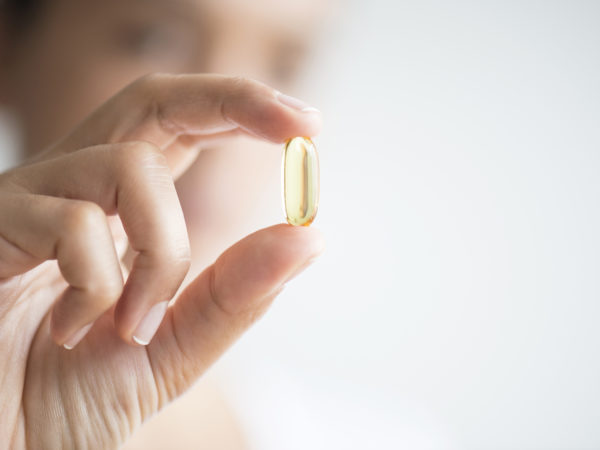 Woman holding omega 3 capsule.