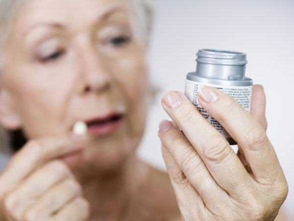 A senior woman holding a bottle of pills